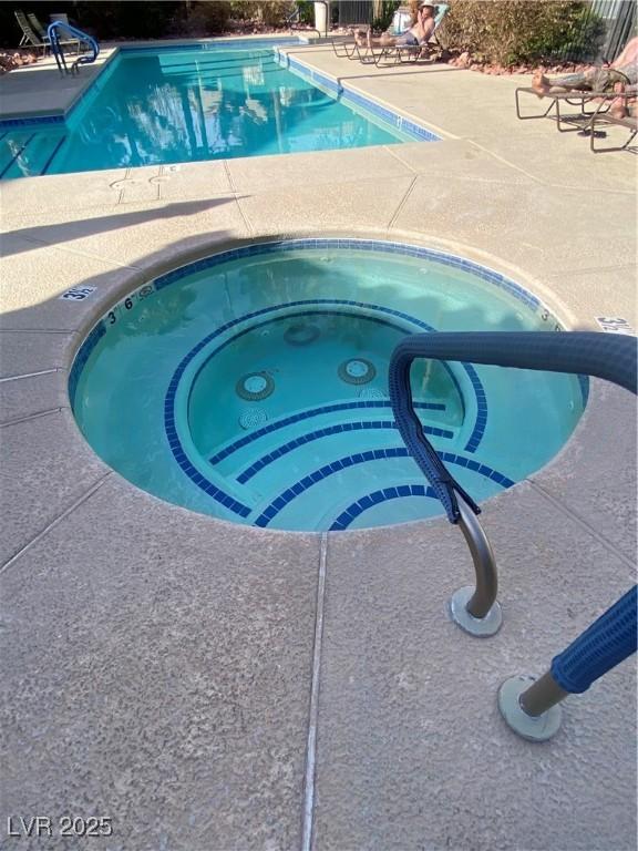 community pool featuring a hot tub and a patio