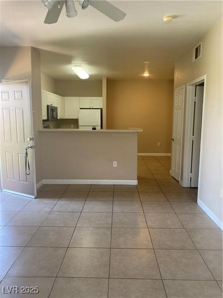 interior space with visible vents, baseboards, light tile patterned flooring, and a ceiling fan