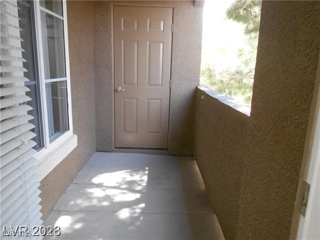 view of exterior entry with stucco siding and a balcony