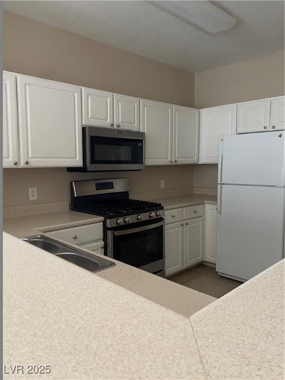 kitchen featuring white cabinetry, light countertops, appliances with stainless steel finishes, and a sink