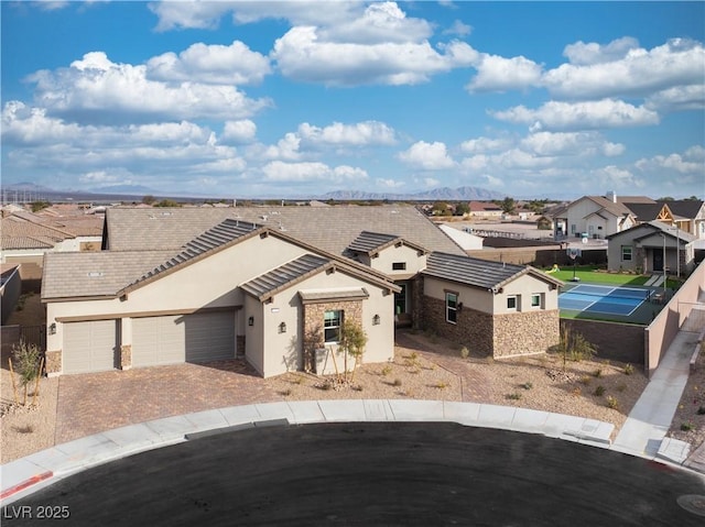 view of front of property featuring a tile roof, an attached garage, a residential view, and stucco siding