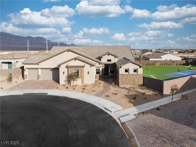 view of front of property with a garage, decorative driveway, fence, and a residential view