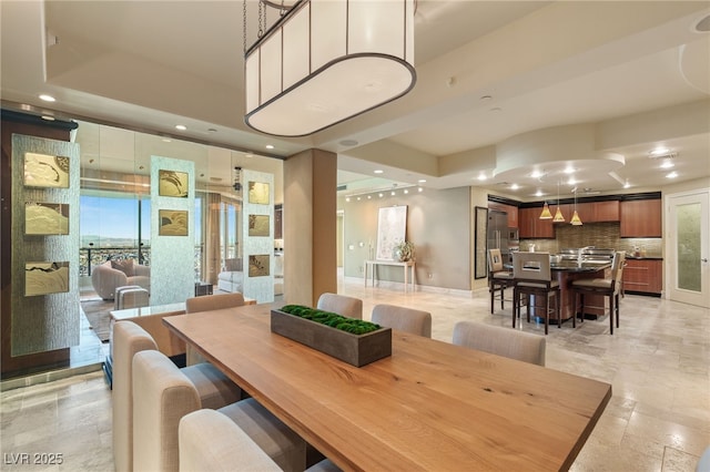 dining area with recessed lighting, a tray ceiling, baseboards, and stone tile floors