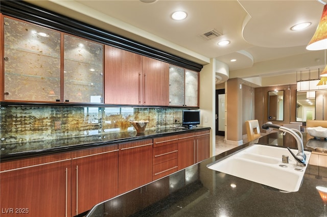 kitchen featuring visible vents, recessed lighting, a sink, glass insert cabinets, and backsplash