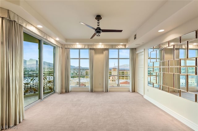 unfurnished sunroom with a wealth of natural light, a mountain view, visible vents, and ceiling fan