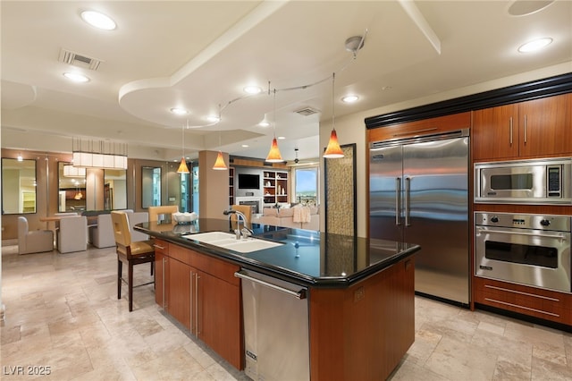 kitchen featuring dark countertops, brown cabinets, built in appliances, and a sink