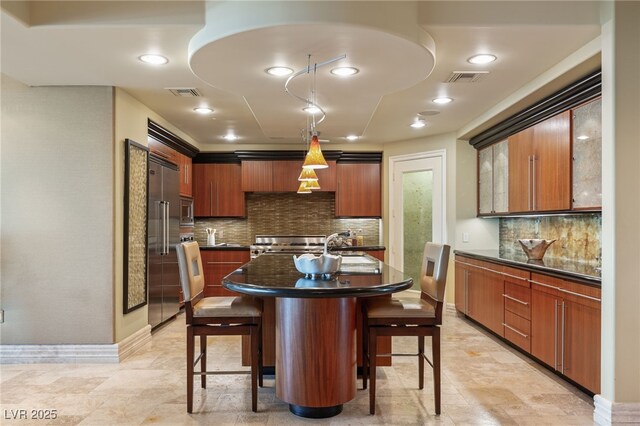 kitchen featuring dark countertops, a kitchen breakfast bar, visible vents, and built in appliances