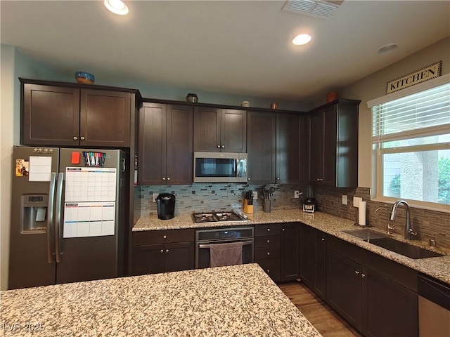 kitchen featuring dark brown cabinetry, visible vents, stainless steel appliances, and a sink