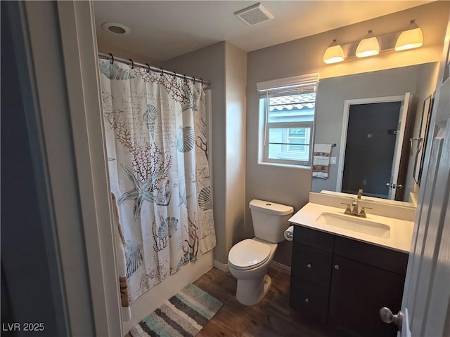 bathroom featuring visible vents, baseboards, toilet, wood finished floors, and vanity