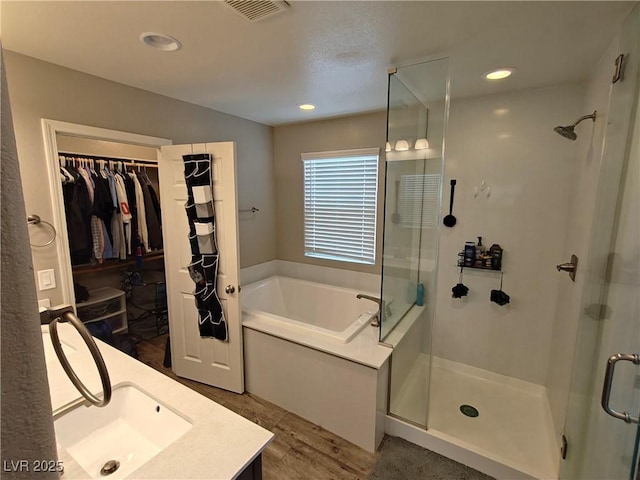 bathroom with a garden tub, visible vents, and a stall shower