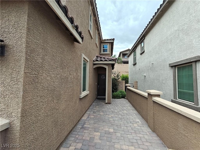 entrance to property featuring a patio area, a tiled roof, fence, and stucco siding