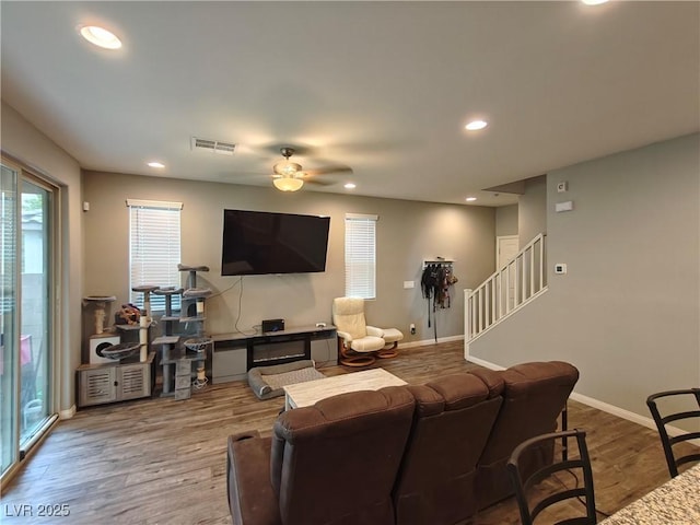 living area with recessed lighting, visible vents, wood finished floors, and stairs