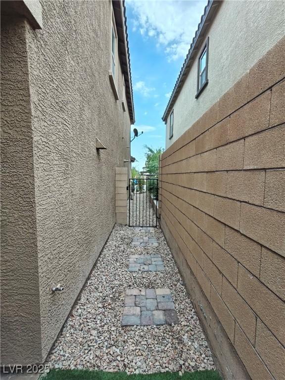 view of side of property featuring a gate, stucco siding, and fence