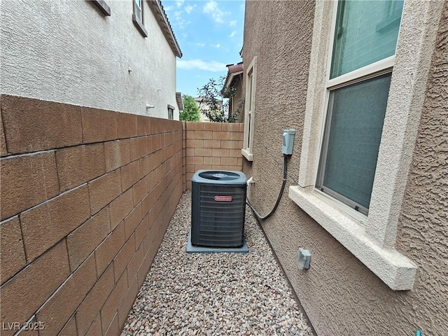 details with stucco siding, central AC unit, and fence