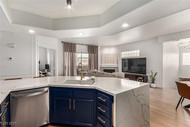 kitchen with a sink, stainless steel dishwasher, a raised ceiling, blue cabinets, and open floor plan