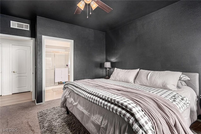 carpeted bedroom featuring ensuite bath, a ceiling fan, and visible vents