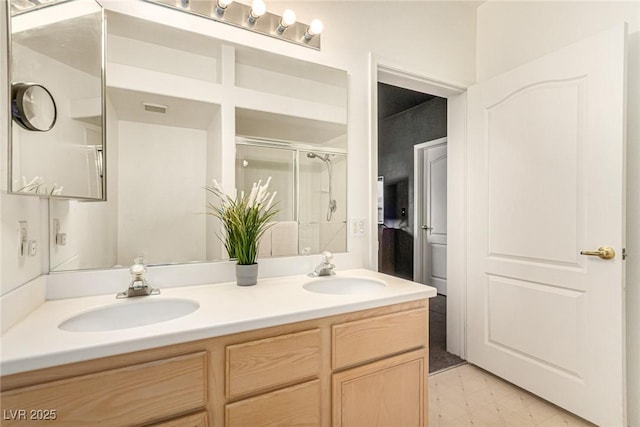 bathroom with double vanity, visible vents, a stall shower, and a sink