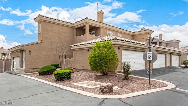 view of front of property featuring aphalt driveway, stucco siding, a tile roof, and a garage