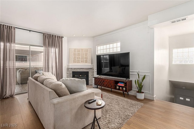 living area featuring visible vents, a fireplace, and wood finished floors