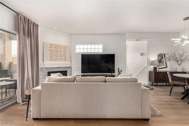 living room with a fireplace, light wood-style floors, and a chandelier