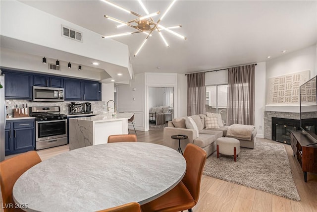 kitchen with visible vents, open floor plan, appliances with stainless steel finishes, blue cabinets, and tasteful backsplash