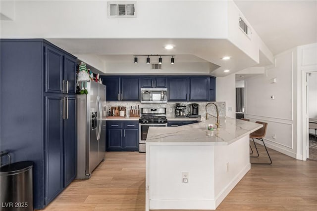 kitchen with visible vents, a peninsula, a sink, appliances with stainless steel finishes, and blue cabinets