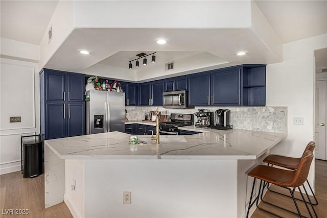 kitchen with blue cabinetry, stainless steel appliances, open shelves, and a peninsula