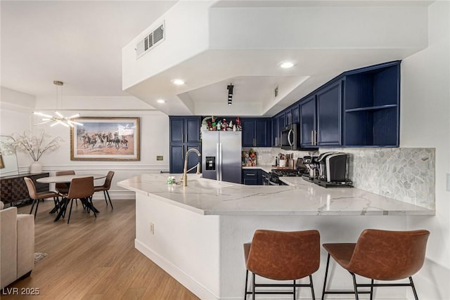 kitchen with visible vents, a peninsula, open shelves, appliances with stainless steel finishes, and blue cabinets