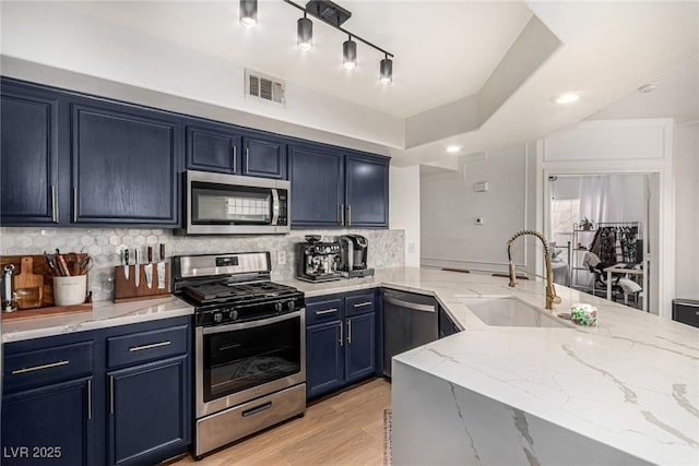 kitchen with blue cabinets, visible vents, a sink, appliances with stainless steel finishes, and light stone countertops