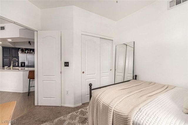 bedroom with carpet, visible vents, stainless steel fridge, and a closet