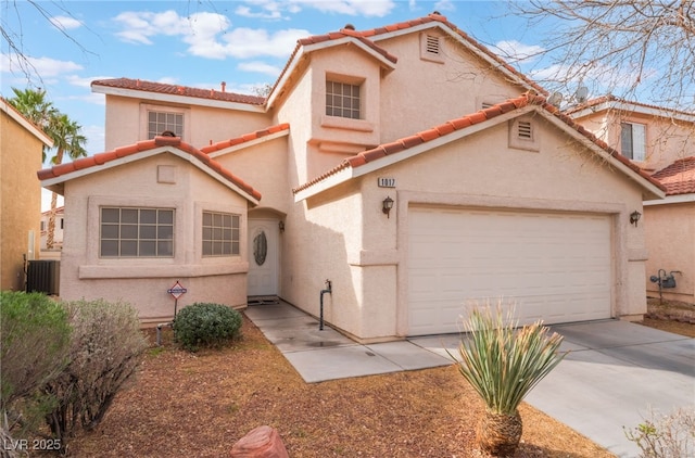 mediterranean / spanish-style home featuring a tiled roof, stucco siding, driveway, and central AC