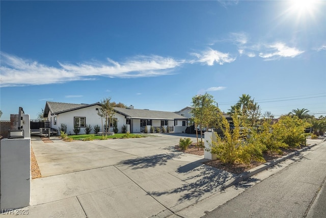 ranch-style home with stucco siding, driveway, and a gate