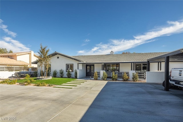 view of front of property with fence, a tile roof, a front yard, stucco siding, and a chimney