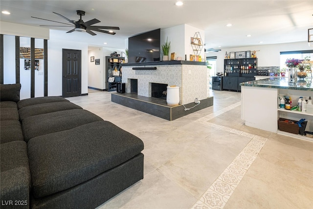 living room with a tiled fireplace, recessed lighting, and ceiling fan