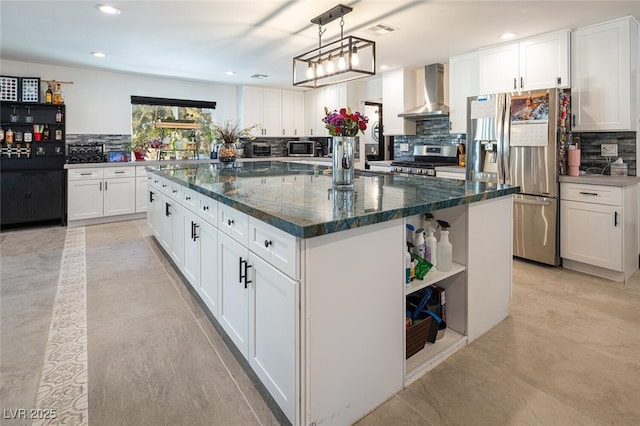 kitchen with open shelves, a kitchen island, appliances with stainless steel finishes, white cabinets, and wall chimney range hood