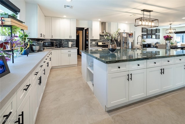 kitchen with open shelves, a kitchen island with sink, white cabinets, wall chimney range hood, and backsplash