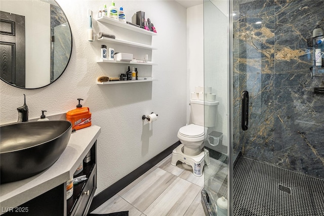 bathroom featuring a marble finish shower, baseboards, toilet, a textured wall, and vanity