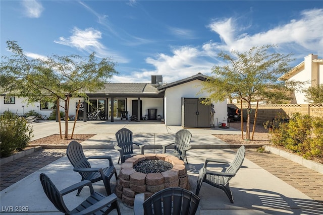 rear view of property with stucco siding, fence, an outdoor fire pit, cooling unit, and a patio area