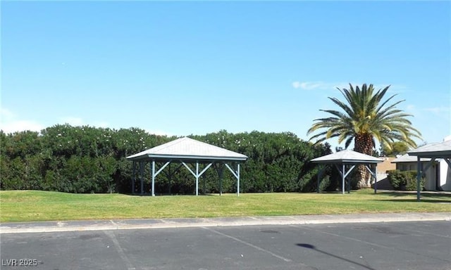 view of property's community featuring a gazebo, a lawn, and a wooded view