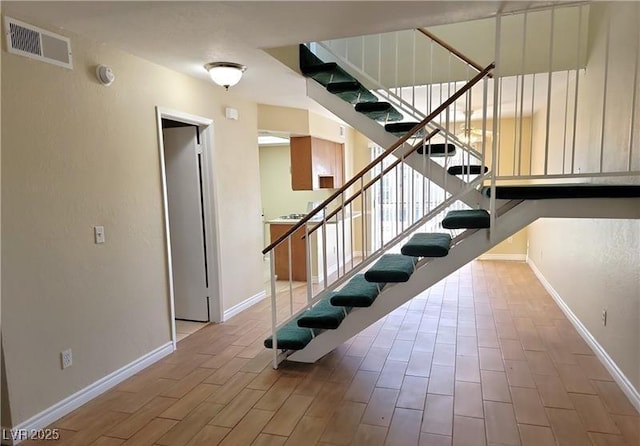 staircase featuring visible vents, baseboards, and wood finished floors