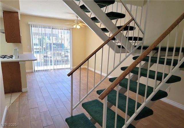 staircase with baseboards, wood finished floors, and a ceiling fan