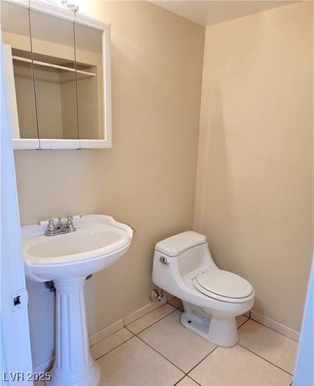 bathroom with tile patterned flooring, toilet, and baseboards