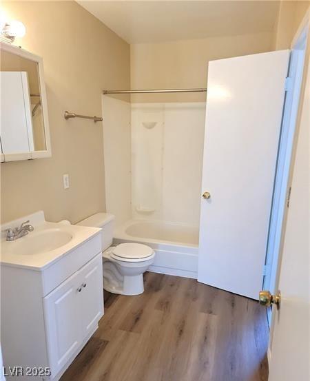 full bath with shower / bathing tub combination, toilet, wood finished floors, and vanity