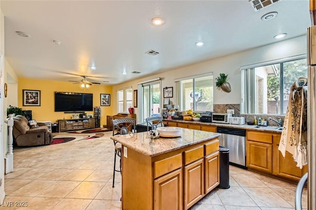 kitchen with visible vents, a sink, light stone counters, stainless steel dishwasher, and light tile patterned floors