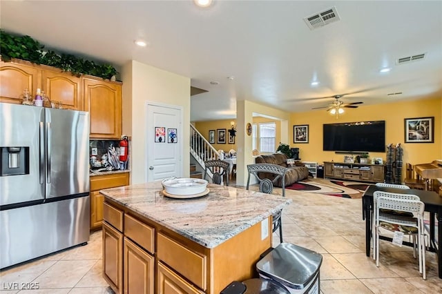 kitchen featuring light stone counters, visible vents, stainless steel fridge with ice dispenser, and light tile patterned floors