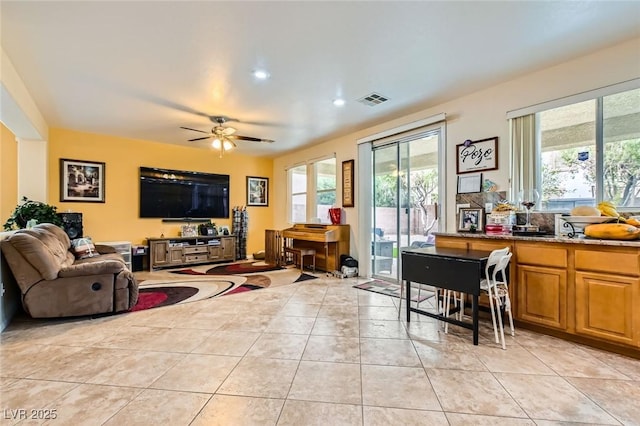 living area featuring light tile patterned floors, visible vents, plenty of natural light, and ceiling fan