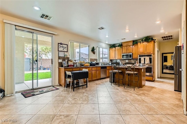 kitchen with a breakfast bar, decorative backsplash, visible vents, and stainless steel appliances