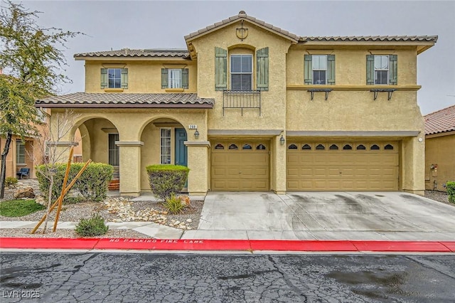 mediterranean / spanish home featuring concrete driveway, a tiled roof, a garage, and stucco siding