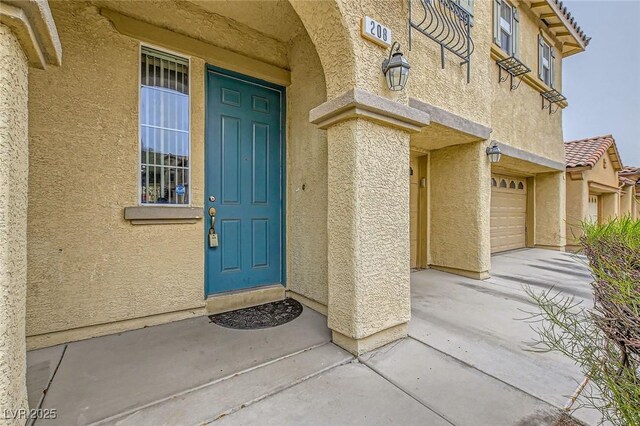 doorway to property featuring stucco siding and a garage