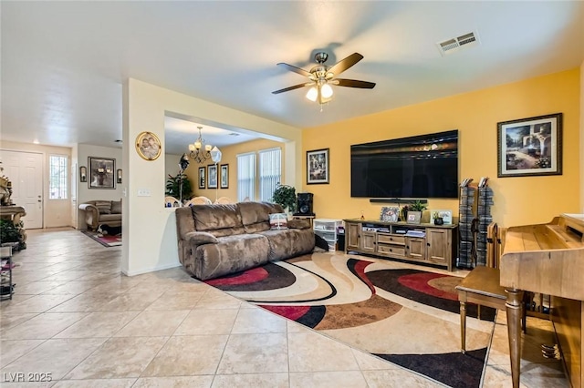 living room with light tile patterned floors, visible vents, baseboards, and ceiling fan with notable chandelier